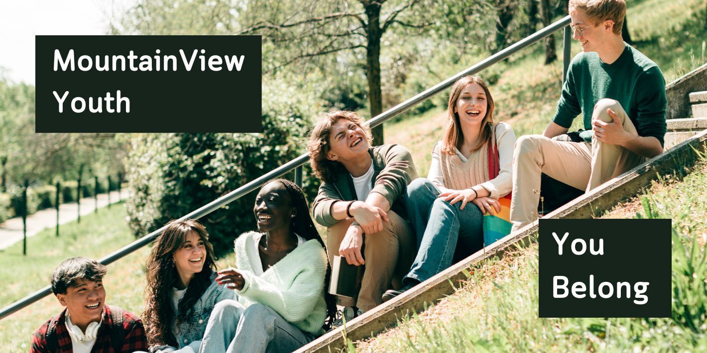 A group of teens sit on a grassy slope